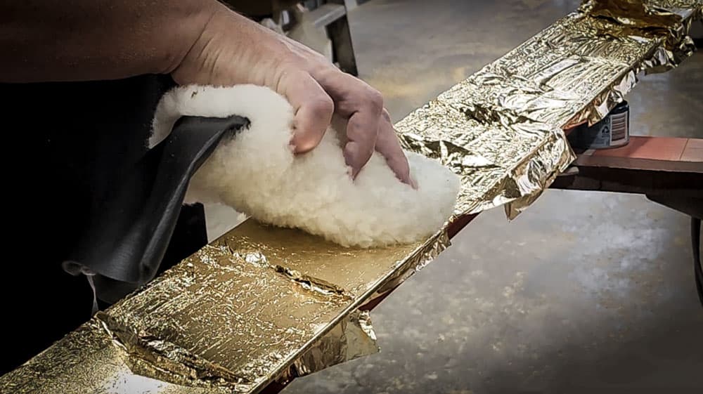 Scott Dawson expertly layers gold leaf onto a handcrafted frame in the gold coast workshop