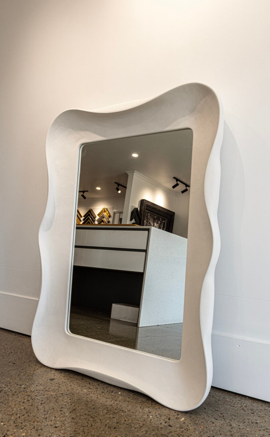 A handmade frame around a mirror with scalloped or wavy edges in a gesso finish, made by dawsons handcrafted gold coast for interior designer Phoebe Nicol